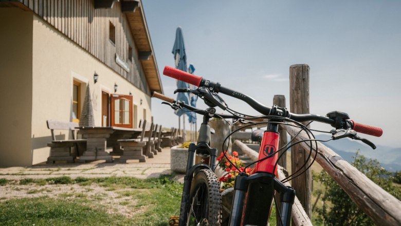 Almreserlhaus, Schneeberg, hut, Schneebergland, Vienna Alps in Lower Austria, © Wiener Alpen/Sophie Menegaldo A mountain bike in front of the Almreserlhaus on the Schneeberg, with benches in the background