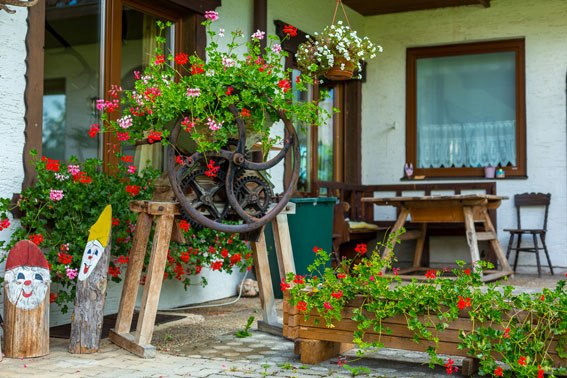 Hiking Hotel Bruckerhof, © Wiener Alpen / Christian Kremsl A rustic garden with flowers and wooden decorations in front of a building.