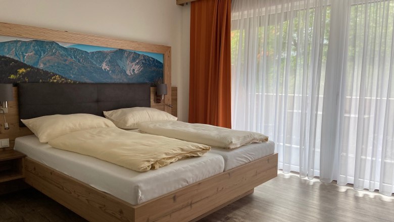 Double room, © Wieneralpen Modern double room with large bed, mountain picture on the wall and large windows with curtains.