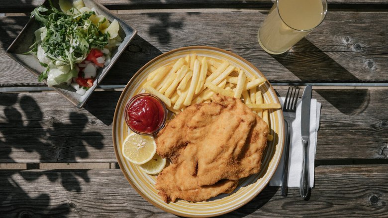 Damböckhaus, Schneeberg, hut, Schneebergland, Vienna Alps in Lower Austria, © Wiener Alpen/Sophie Menegaldo Schnitzel with French fries, salad, and a drink on a wooden table at the Damböckhaus on Schneeberg