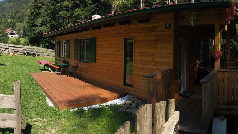 Vacation home, © Marianne Gschaider A wooden holiday home with terrace in a green, wooded setting.