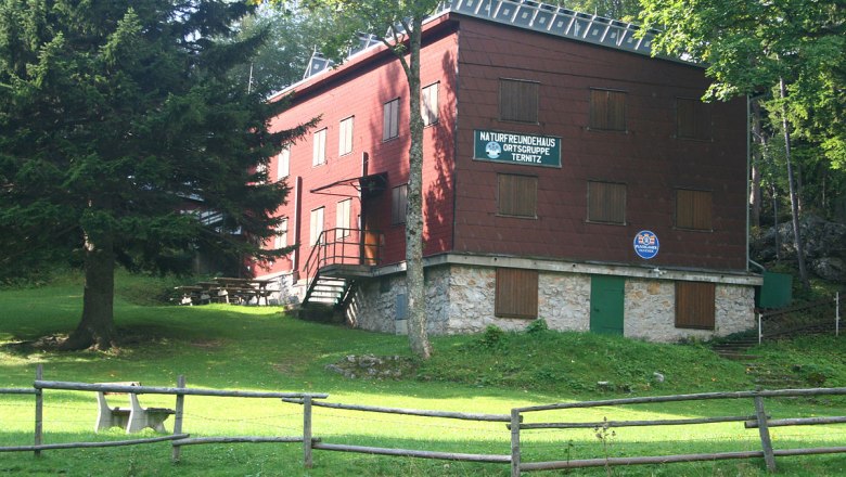 Ternitzer Hut, © WA-Wien A red building with wooden cladding, surrounded by trees and a meadow, with a sign "Naturfreundehaus Ortsgruppe Ternitz".