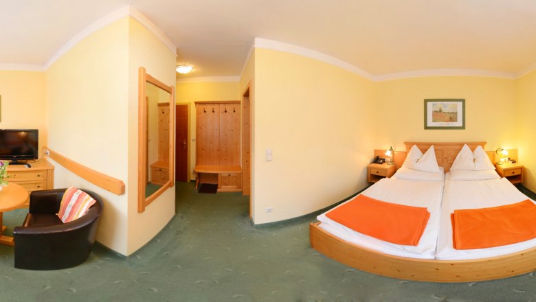 Exclusive room with a view of the Schneeberg, © Gasthof Schmirl Panorama of a hotel room with double bed, table, two armchairs and TV.