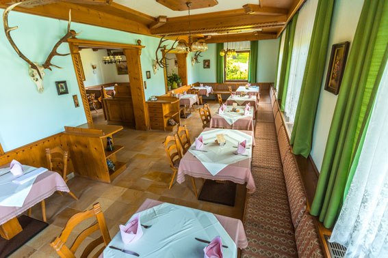 Dine well at the Bruckerhof, © Wiener Alpen / Christian Kremsl Cozy restaurant with wooden furniture and tablecloths, decorated with antlers on the walls.