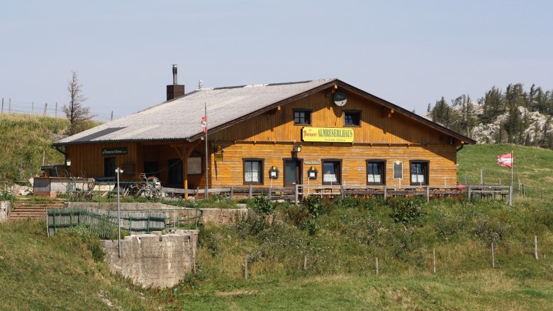 Almreserhaus, © Bwag/Commons Ein traditionelles Holzgebäude in alpiner Landschaft mit der Aufschrift 'Almreserhaus'.