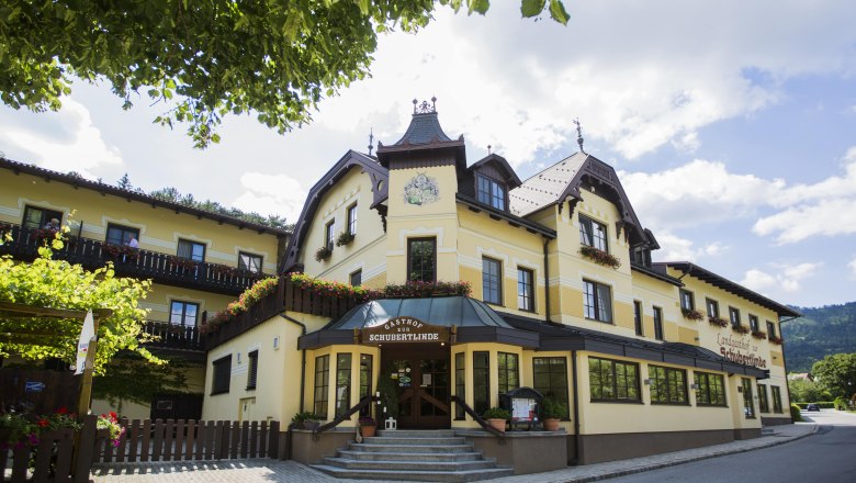 Alpen-Aktiv Country Inn "Zur Schubertlinde", © Patrick Haberler Yellow inn with flowers and blue sky.