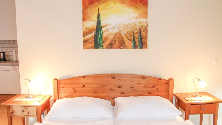 Apartment 30m², © Haus Lenz Bedroom with wooden bed, two bedside tables and a landscape painting on the wall.