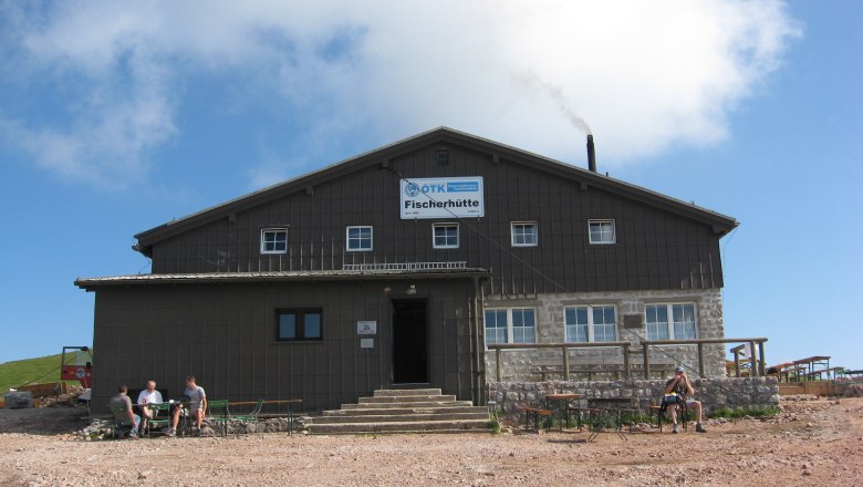 Ein gro&szlig;es Geb&auml;ude mit der Aufschrift 'Fischerh&uuml;tte' vor blauem Himmel.