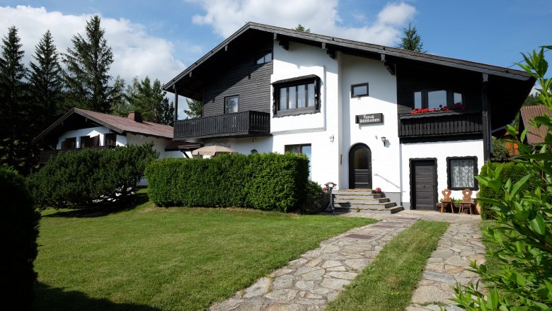 Haus Almboden, © Fam. Ullram-Haberichter Ein zweistöckiges Haus mit schwarzem Holz und weißen Wänden, umgeben von einem gepflegten Garten und Bäumen.