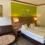 Gem&uuml;tliches Doppelzimmer mit Holzm&ouml;beln, Sofa, Tisch und Wanddekoration.