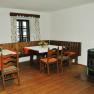 Cozy dining area with wooden table, chairs, corner bench and stove.