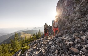 Mann und Frau wandern auf dem Schneeberg. Im Hintergrund die Morgensonne