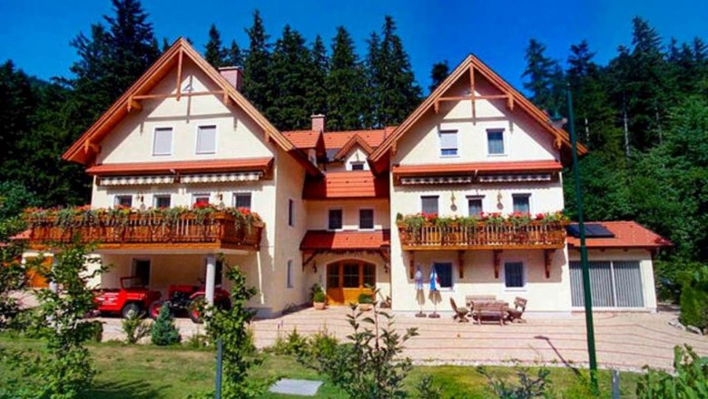 Haus Lenz, © Haus Lenz Großes Haus mit zwei Giebeln, Balkonen und rotem Dach, umgeben von Bäumen.