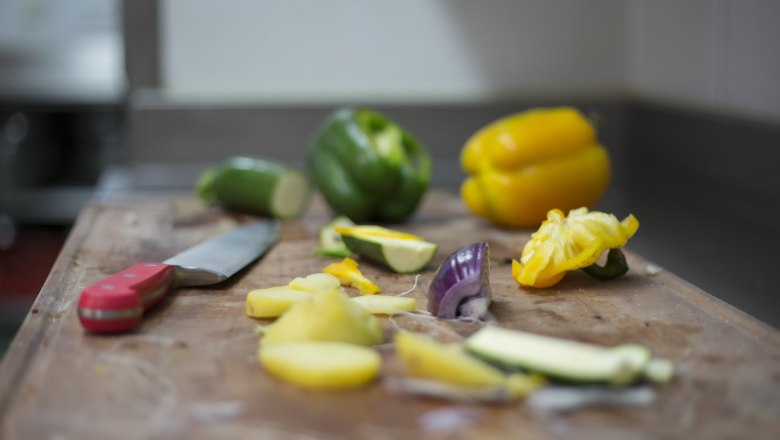 Gem&uuml;se und Messer auf einem Schneidebrett in einer K&uuml;che.