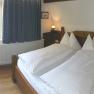 Cozy bedroom with double bed, wooden furniture and window with a view of the greenery.