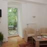 Living room with two beige armchairs, wooden table, TV and balcony with table and chairs.