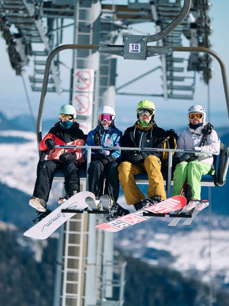 4 Personen sitzen in der Schneeberg Sesselbahn in Wintersportausr&uuml;stung