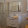 Modern bathroom with shower, washbasin and yellow towels.