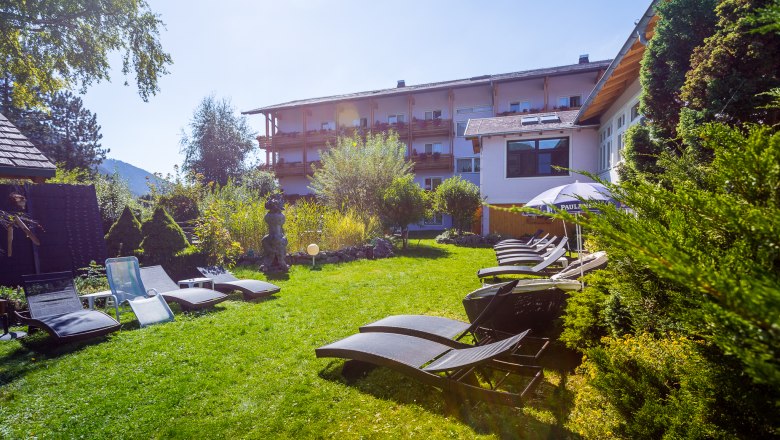 Garten mit Liegen vor dem rosa Haus