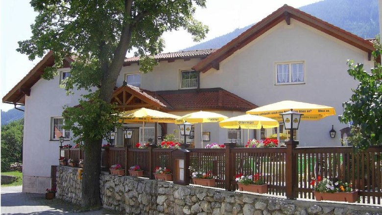 Gasthof mit Terrasse und gelben Sonnenschirmen.