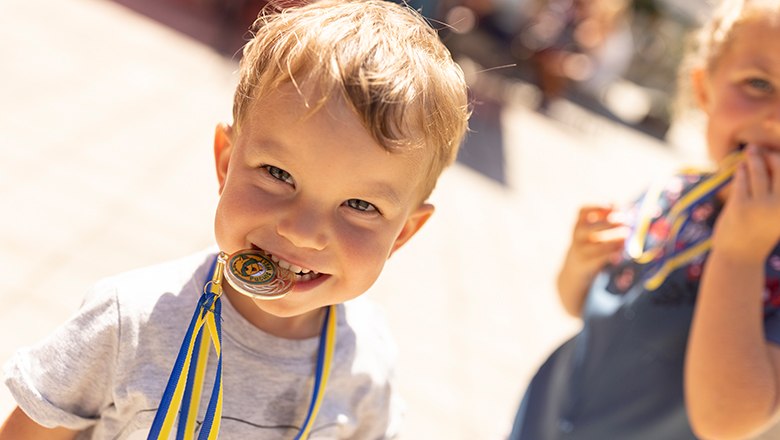 Kind hat eine goldene Medaille im Mund