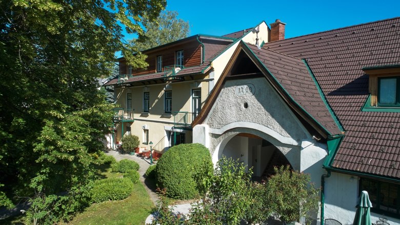 Landhaus Puchbergerhof mit Garten und B&auml;umen im Vordergrund.