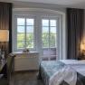 Ein gemütliches Hotelzimmer mit Doppelbett, Fenster mit Bergblick, Schreibtisch und Blumen.