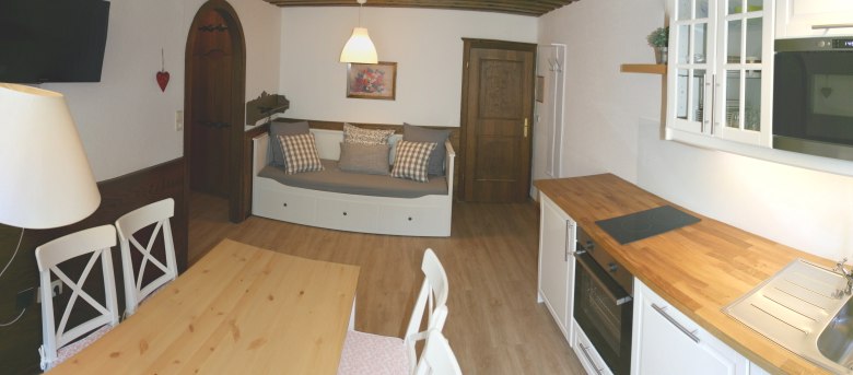 Gem&uuml;tliches Apartment mit K&uuml;che, Esstisch und Sofa.