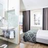 Modernes Hotelzimmer mit Doppelbett und Glasdusche.