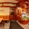 Panorama of a cozy restaurant with wooden furniture and decorative lamps.