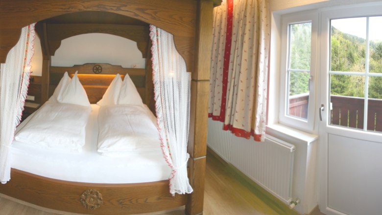 Gem&uuml;tliches Schlafzimmer mit Himmelbett und Balkonblick ins Gr&uuml;ne.