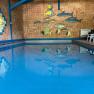 Innenpool mit blauer Wasseroberfl&auml;che und Wanddekoration aus Fischen.