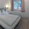 Bedroom in a vacation home with double bed, TV and window with curtains.