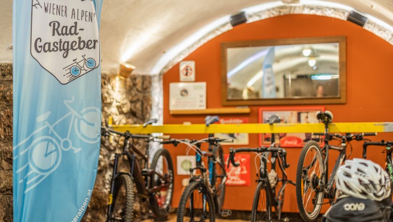 Fahrradgarage mit Fahrr&auml;dern und einem Banner der Wiener Alpen Rad-Gastgeber.