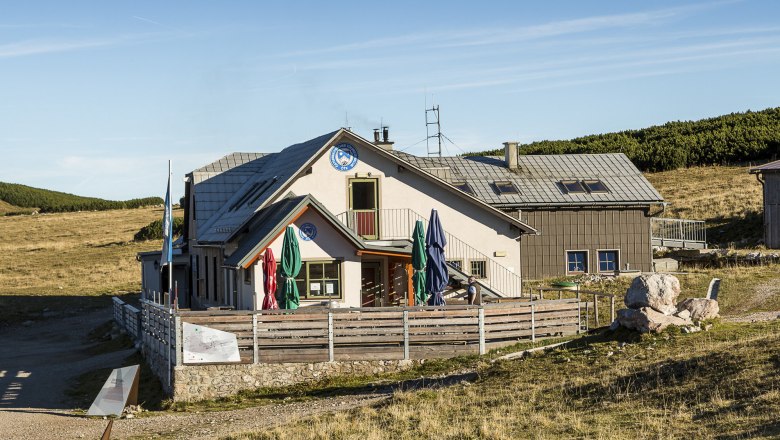 Das Damb&ouml;ckhaus am Schneeberg in einer sonnigen Berglandschaft mit blauem Himmel.