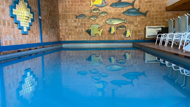 Innenpool mit blauer Wasseroberfl&auml;che und Wanddekoration aus Fischen.