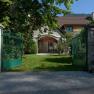 Open green gate leads to a house with garden.