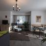 Cozy living room with sofa, armchair, dining table and plants.
