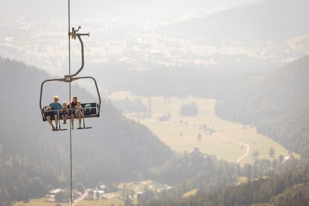 Eltern sitzen mit ihrem kleinen Sohn und ihrer kleinen Tochter in der Schneeberg Sesselbahn