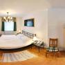 Small bedroom with double bed, bedside tables, TV, microwave and chair.