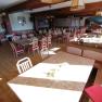 An empty dining room with wooden tables and red chairs at Gasthof Mohr.