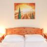 Bedroom with wooden bed, two bedside tables and a landscape painting on the wall.