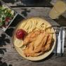 Schnitzel with French fries, salad, and a drink on a wooden table at the Damb&ouml;ckhaus on Schneeberg