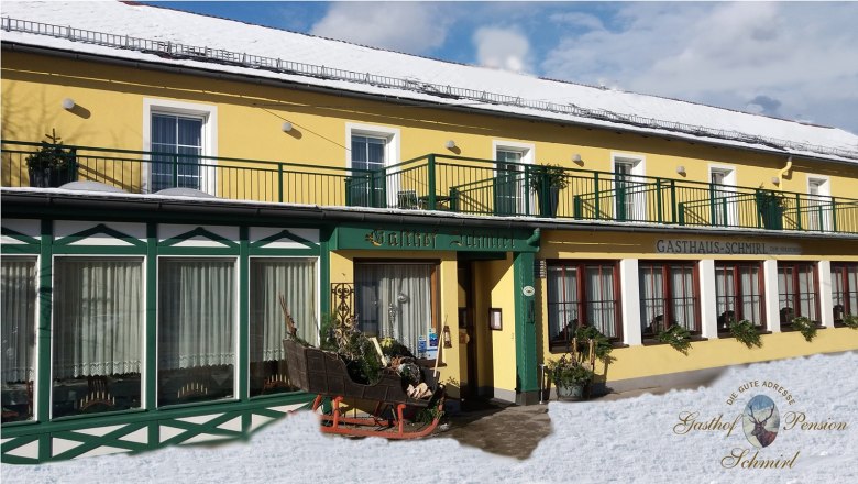 Schmirl Inn, © Bernhard Schmirl Yellow building with green accents, labeled Gasthof Schmirl, in the snow.