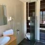 Modernes Badezimmer mit Waschbecken, Spiegel, Handt&uuml;chern, Toilette und Dusche.