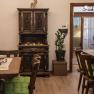 Cozy lounge with wooden furniture, green seat cushions and decorative cupboard.