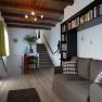 Living room with brown sofa, bookshelf and staircase in the background.