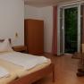 Bedroom with double bed, wardrobe, table and chair, window with curtains.