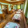 Cozy restaurant with wooden furniture and tablecloths, decorated with antlers on the walls.