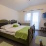 Cozy bedroom with double bed, green comforter and TV on the wall.